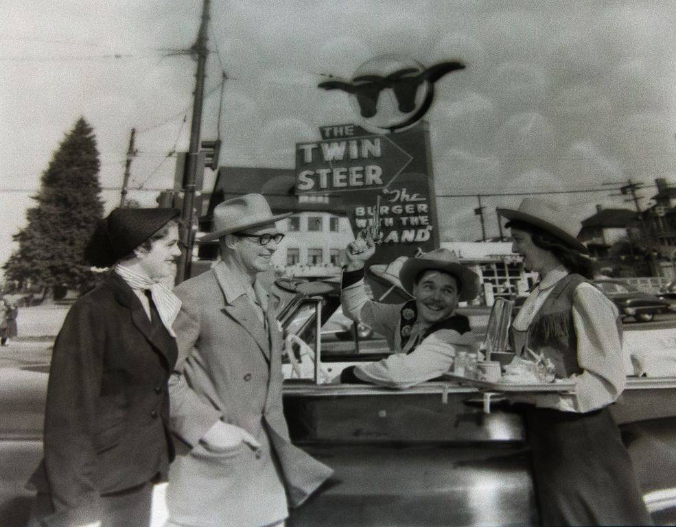 le-driver-carhop-in-western-costumes-neon-sign-twin-steers-brand-on-hamburger-bun-1954-artray-ph.jpg